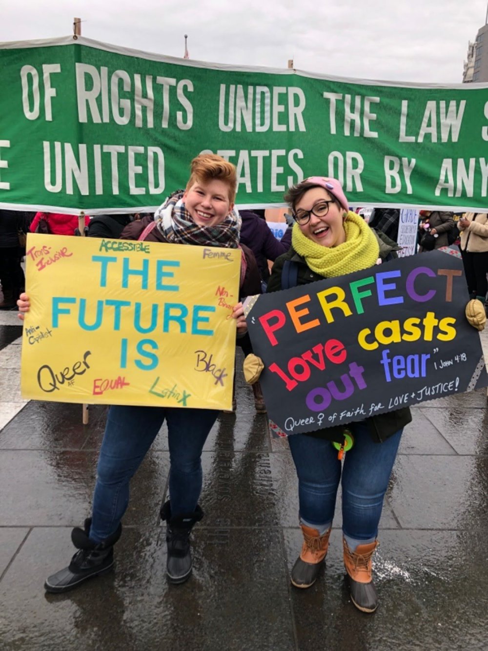 Two women smiling and holding activist signs.