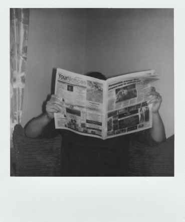 grayscale photography of man reading newspaper