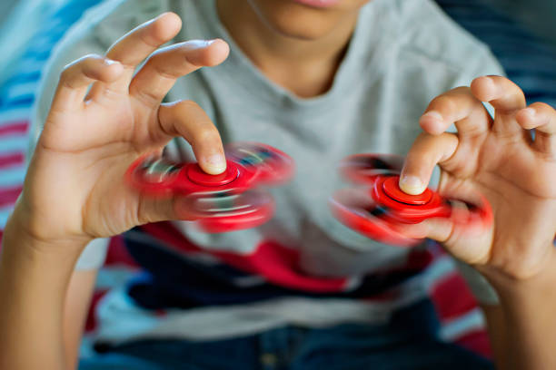 A young boy is pictured with two red fidget spinners.